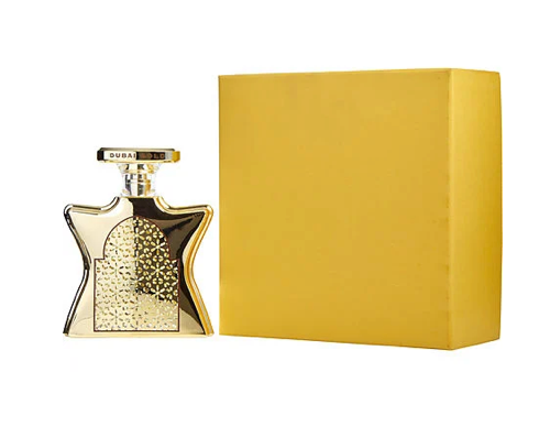 Perfume bottle with gold cap and decorative label next to a matching yellow box on a white background